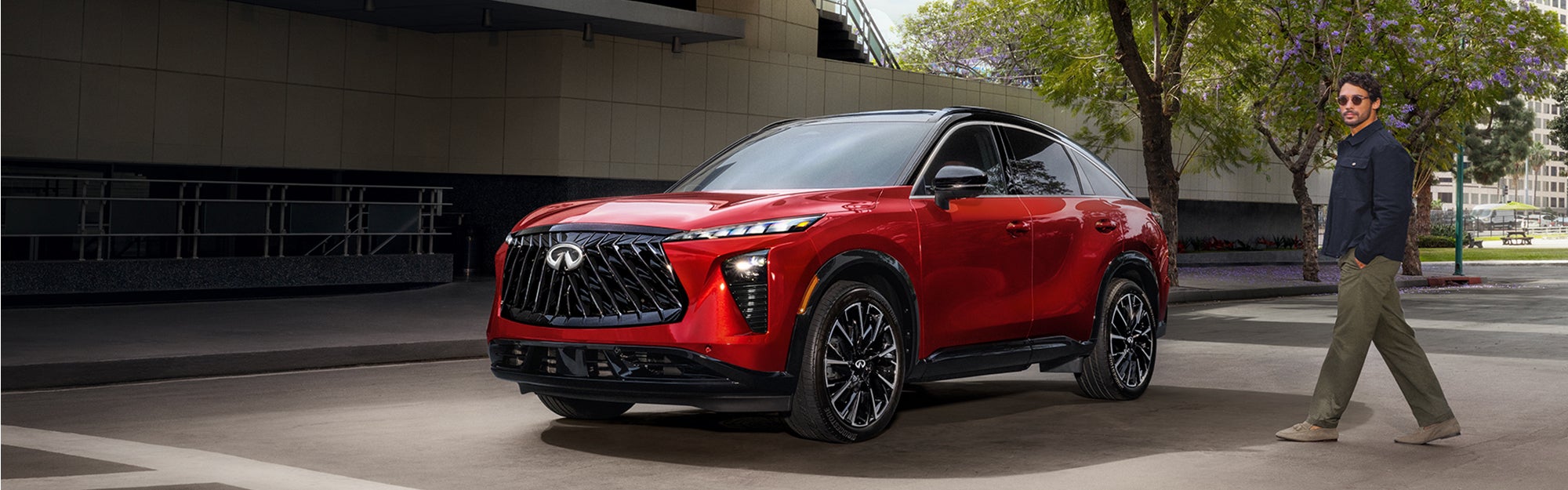 Red Infiniti QX65 SUV parked in an urban setting with a person walking nearby.